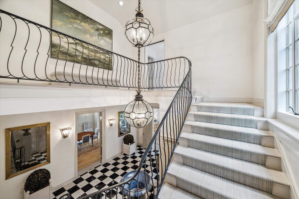 2110 River Oaks Boulevard staircase with metal bannister, looking down to a black-and-white parquet floor