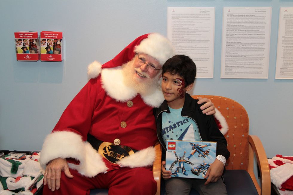 35 A patient smiles with Santa after receiving a gift at Santa visits Texas Children's Cancer Center December 2014