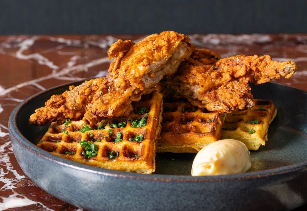 a cast-iron skillet filled with fried quail and waffles
