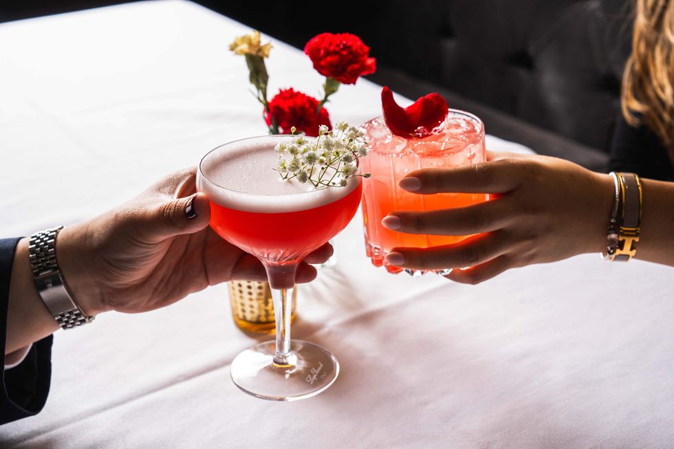 A couple's hands toasting with two cocktails