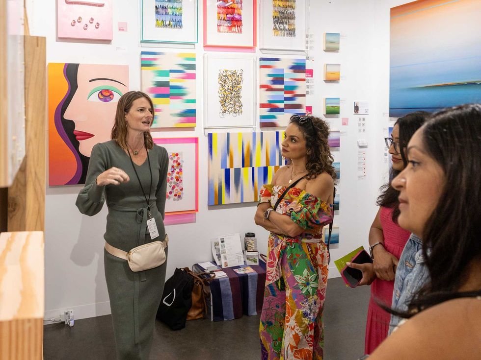 A gallery owner shows off paintings at Affordable Art Fair