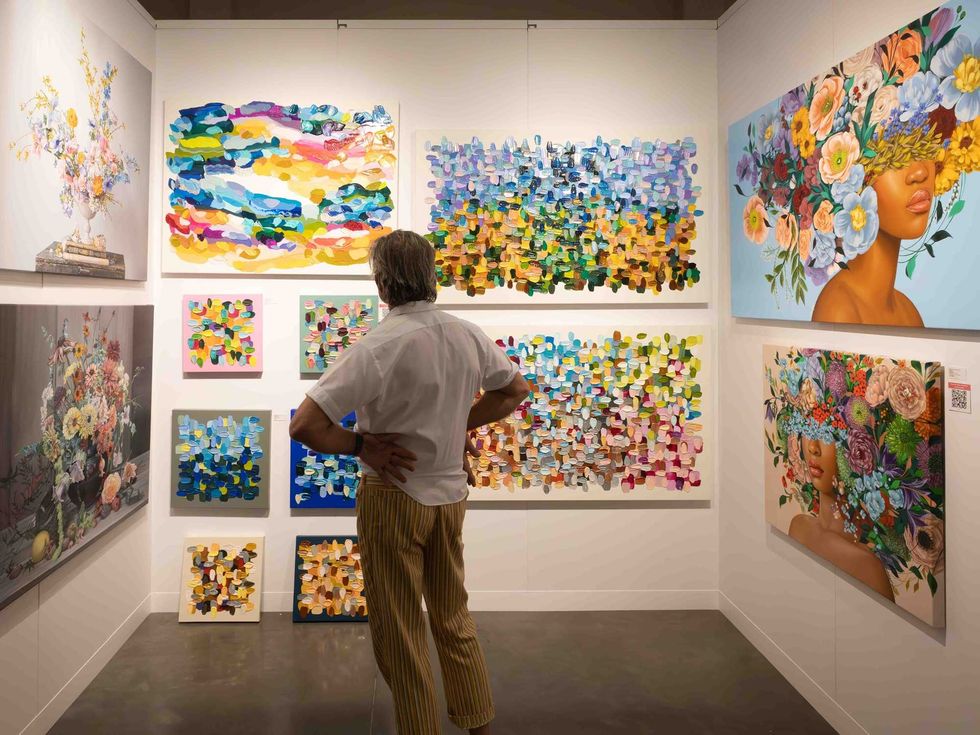 A man staring at a selection of paintings at the Affordable Art Fair