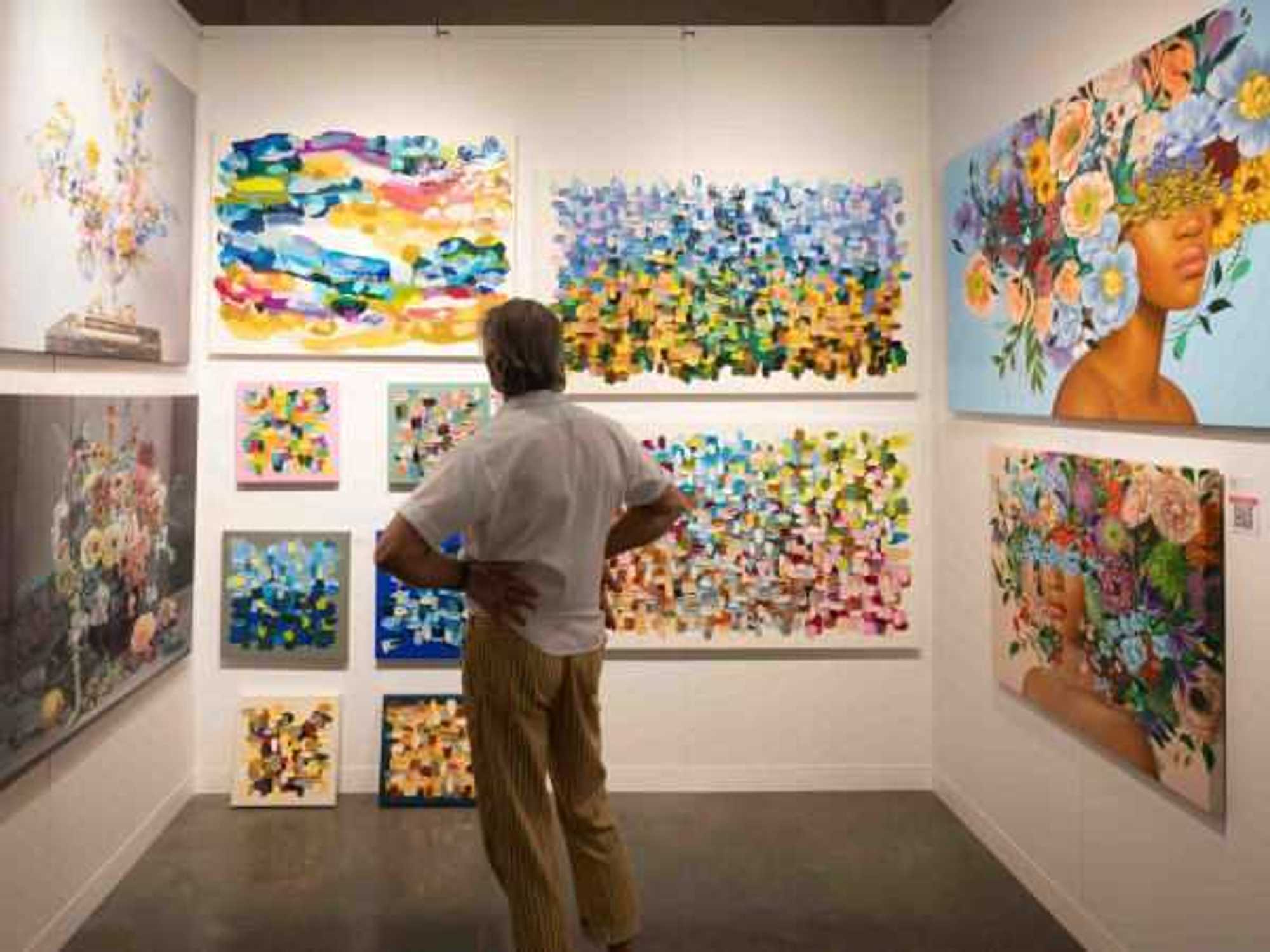 A man staring at a selection of paintings at the Affordable Art Fair