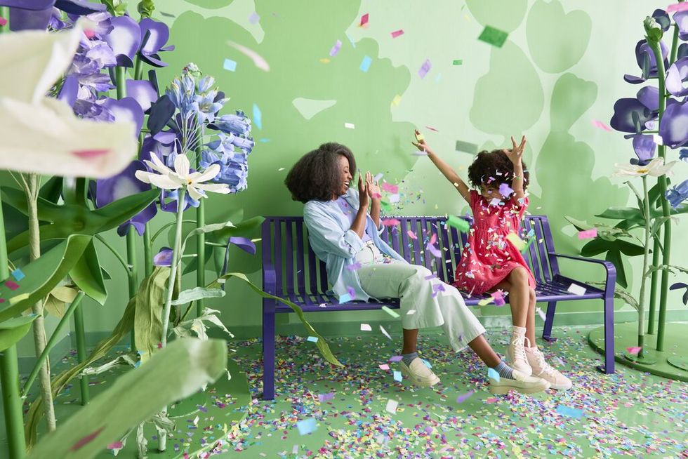 A mom and her daughter playing among confetti flower petals.