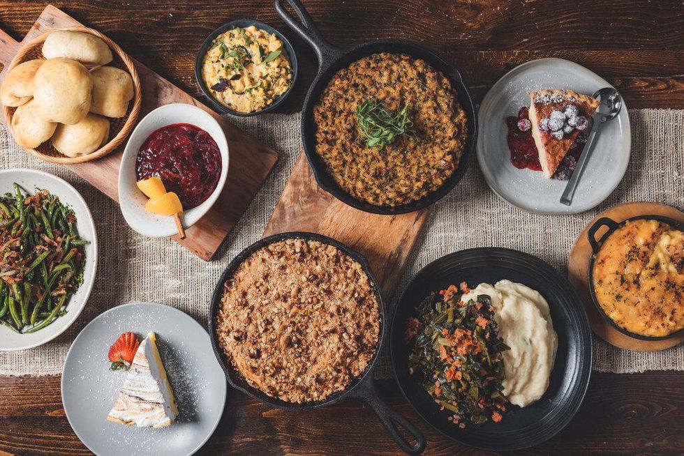 A picture of a table with several side dishes on it including green beans, cranberry sauce, rolls, mashed potatoes, and two slices of pie.