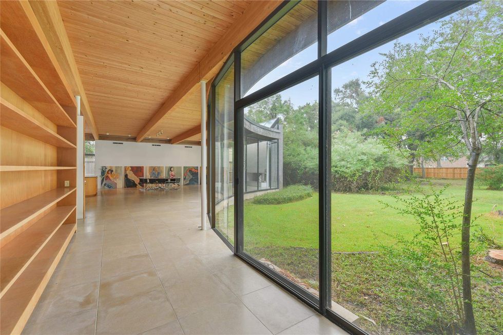 A view into the backyard of 701 Mulberry Lane, with windows on the right and wood built-in shelves on the left.