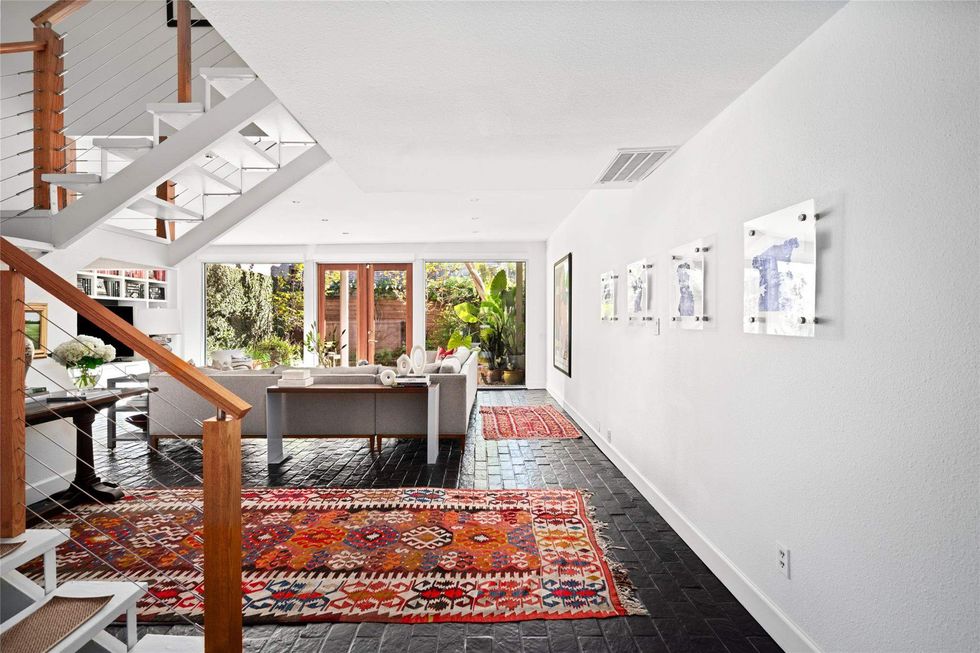 A view of the living room of 1507 Harold Street, showing the zigzag stairs and floor-to-ceiling doors leading to the courtyard
