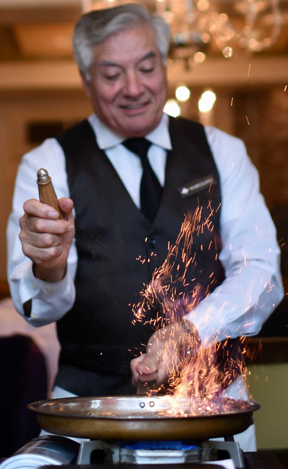 A waiter making Bananas Foster tableside at Brennan's, shaking cinnamon onto a pan to make a flame