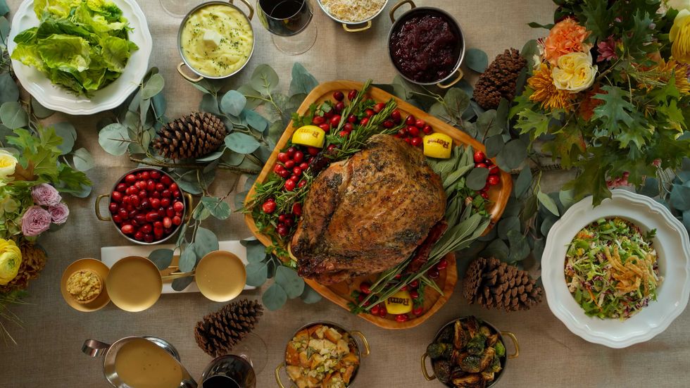 A whole roasted turkey with sides including cranberries, mashed potatoes, and a salad.