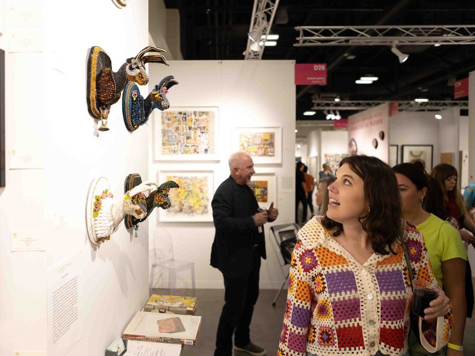 A woman looks at rabit head sculptures at Affordable Art Fair