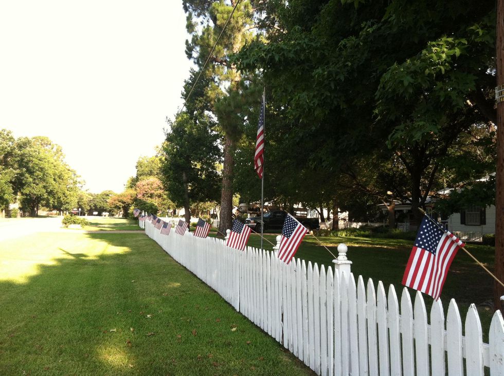 American flags on a white picket fence