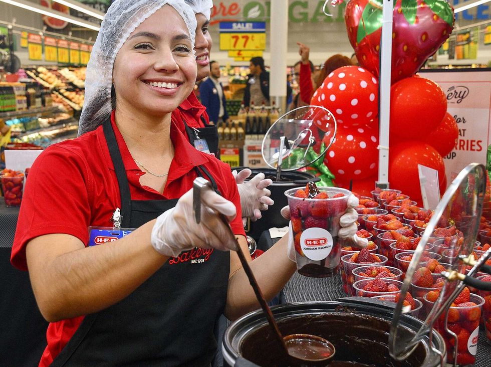 An H-E-B employee ladles ganache over strawberries