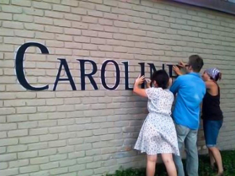 Caroline Collective putting sign letters up on building