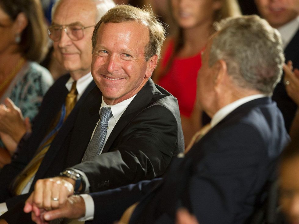 Chairman of Points of Light Neil Bush (C) shakes hands with his father, former US President George H.W. Bush, while attending a White House ceremony to recognize the Points of Light volunteer program July 15, 2013