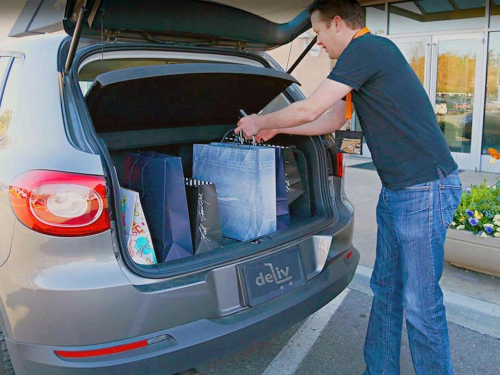 Deliv delivery service with guy putting shopping bags into car