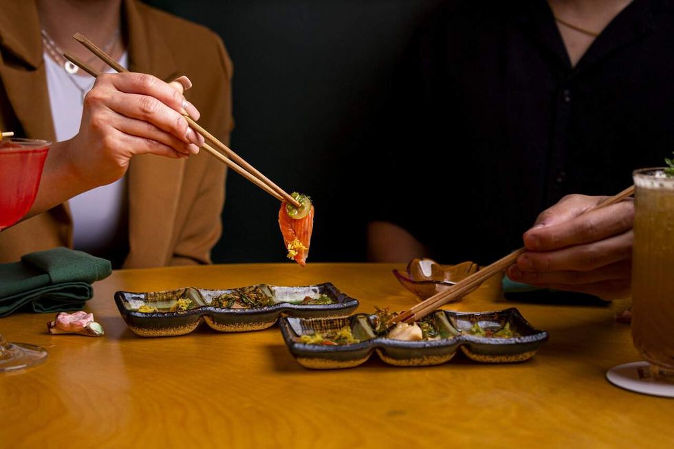 Diners eating sushi with chopsticks at Aya Sushi
