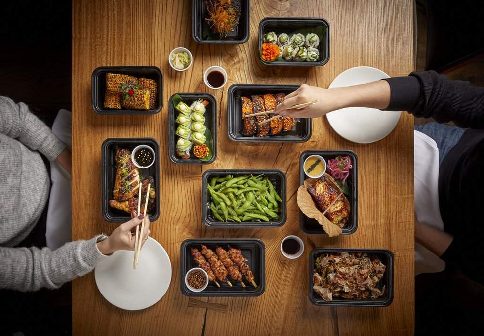 Diners with chopsticks and many dishes from Roka Akor