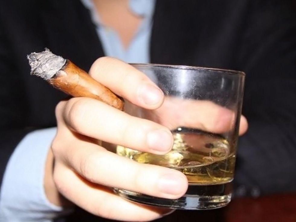 Downing Street Pub & Cigar Bar man's hand holding whiskey and cigar