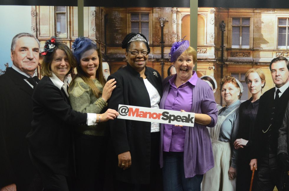 Elaine Roach, Carol Lukes, Rhonda Onwere, Irene Brackenridge pose in front of wall of Downton Abbey characters
