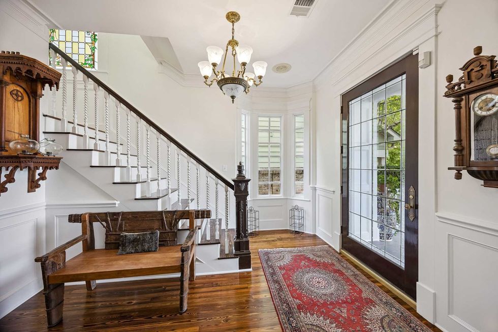 Entryway of 216 E. 26th Street showing a carved wooden staircase, hardwood floors and wide door