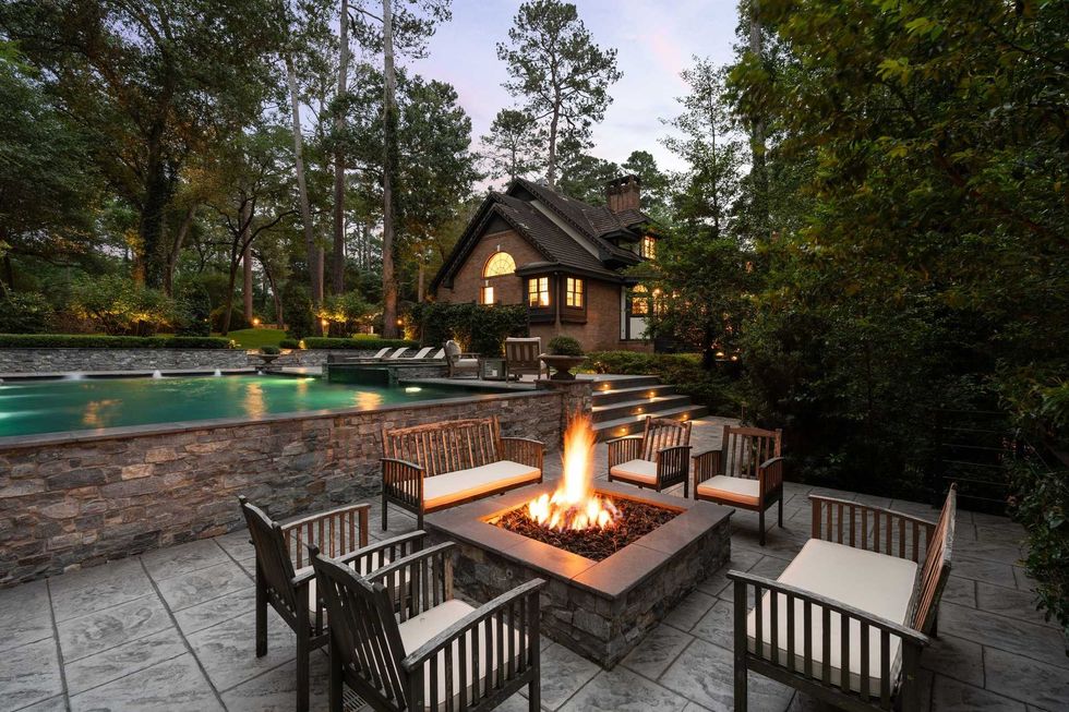 Exterior of the backyard of 23227 Brownwood Lane in Tomball with a firepit surrounded by chairs and the pool in the background