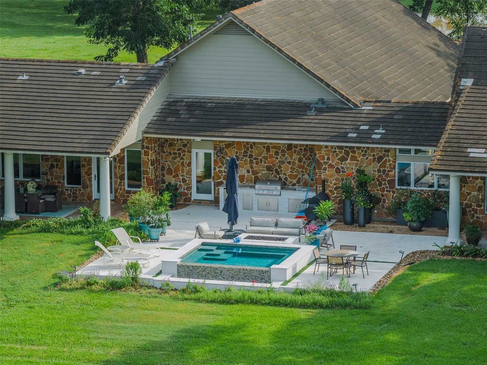 Exterior view of the back of S Lazy S Ranch at 8502 Stansberry Road showing the outdoor kitchen, spa and seating areas