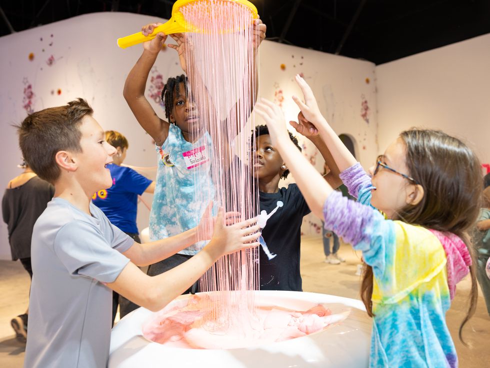 Four kids playing with a giant stream of strands of slime
