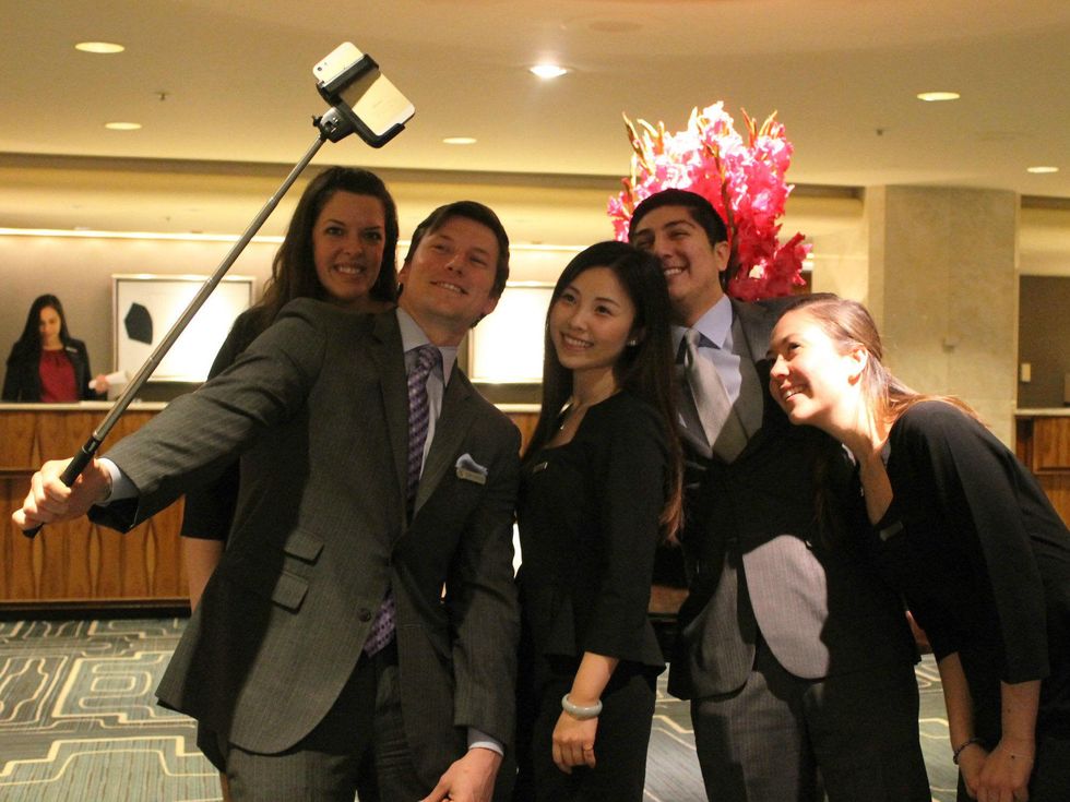 Four Seasons Hotel staff member demonstrate proper use of a Selfie Stick