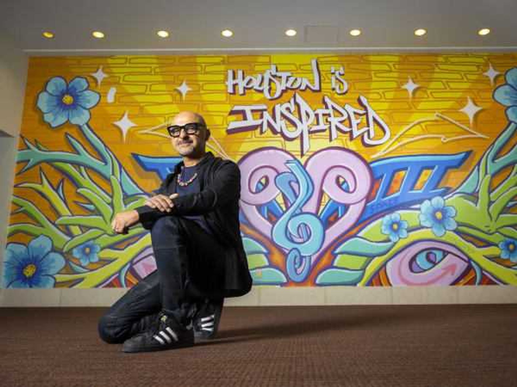 GONZO247 poses in front of his new mural, "Houston is Inspired" inside Hobby Center