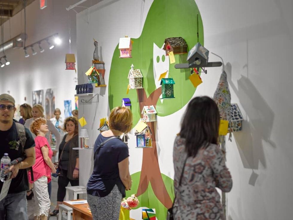 Guests perusing the artist birdhouses on display at Sawyer Yards Artist Stroll