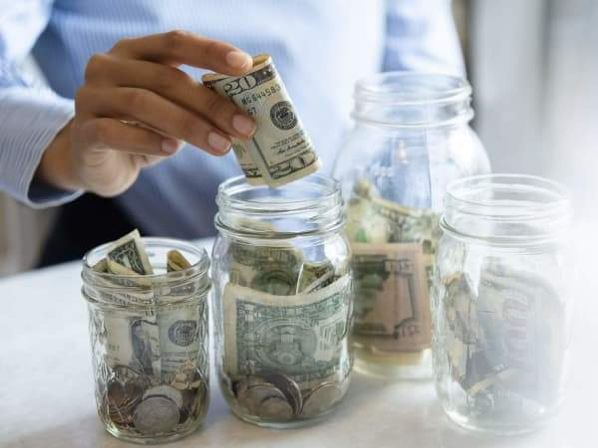 Hand of woman putting money in jar