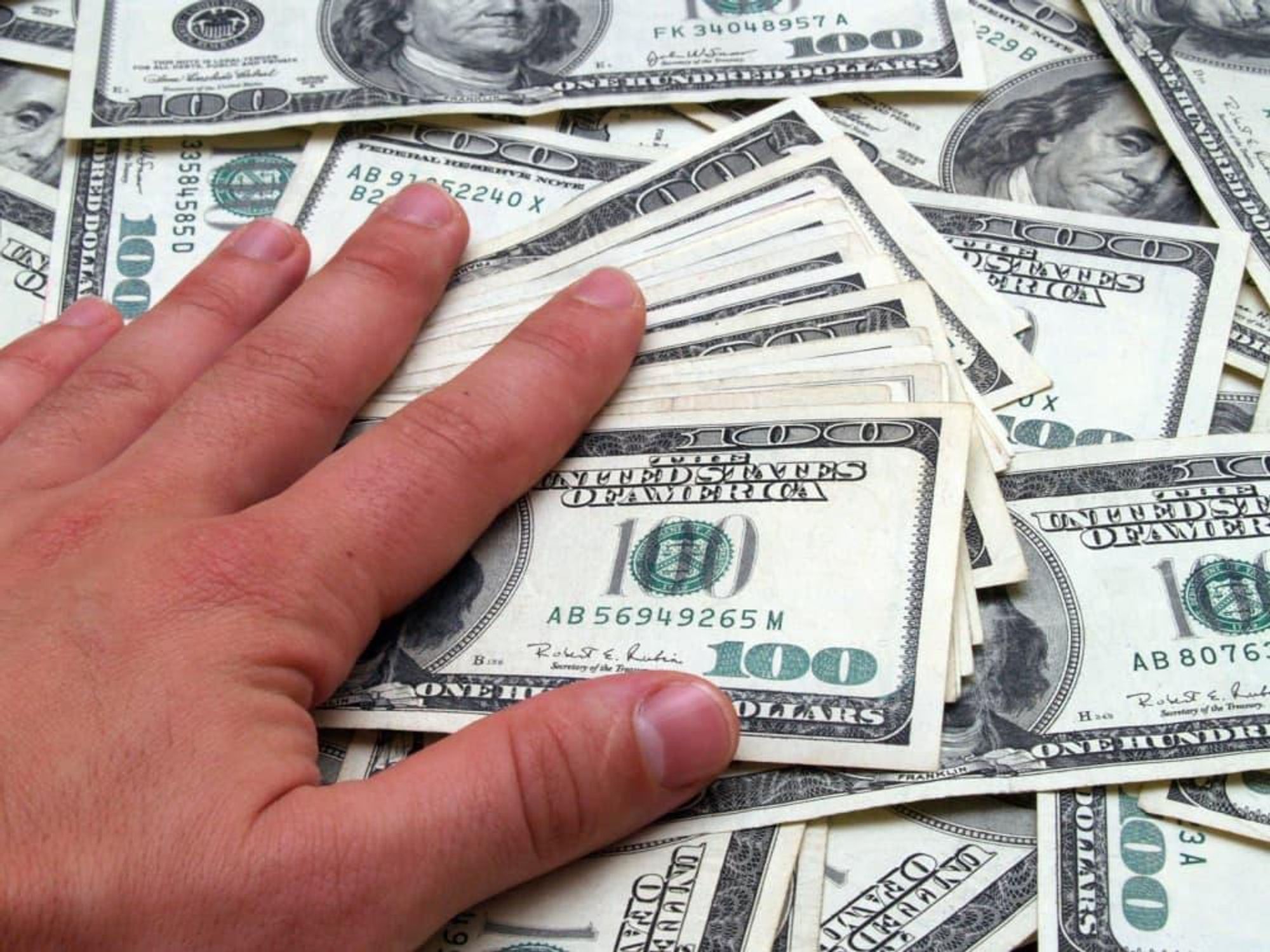 hand on money $100 bills getting rich