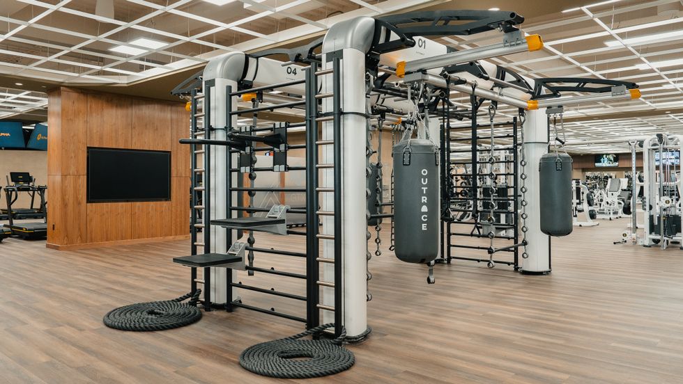 Hanging heavy bags, workout apparatus with ropes and weights and a wall-mounted TV.