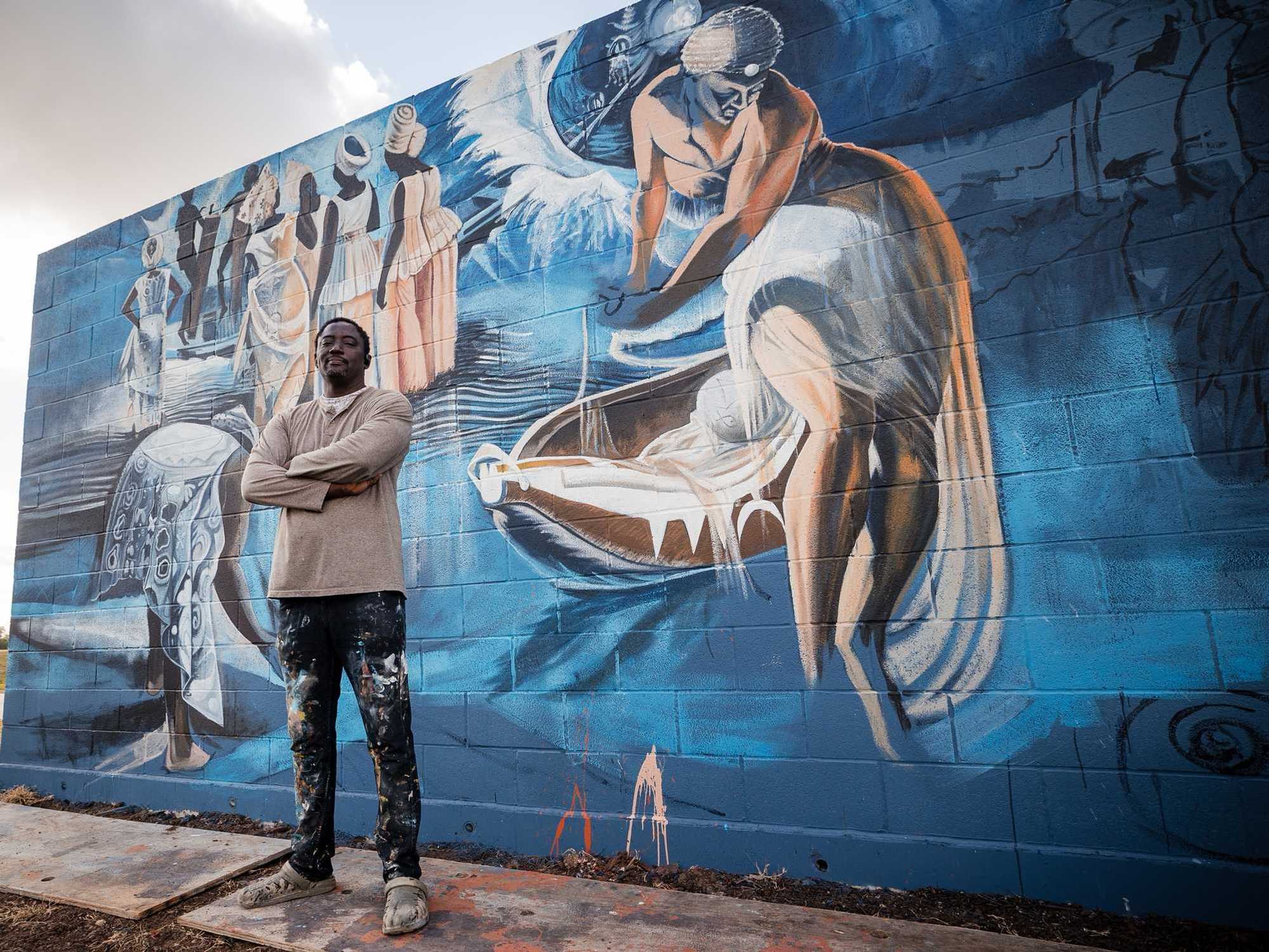 Houston artist Ade Odunfa stands in front of his mural "Salt Marsh" at the Hill at Sims.