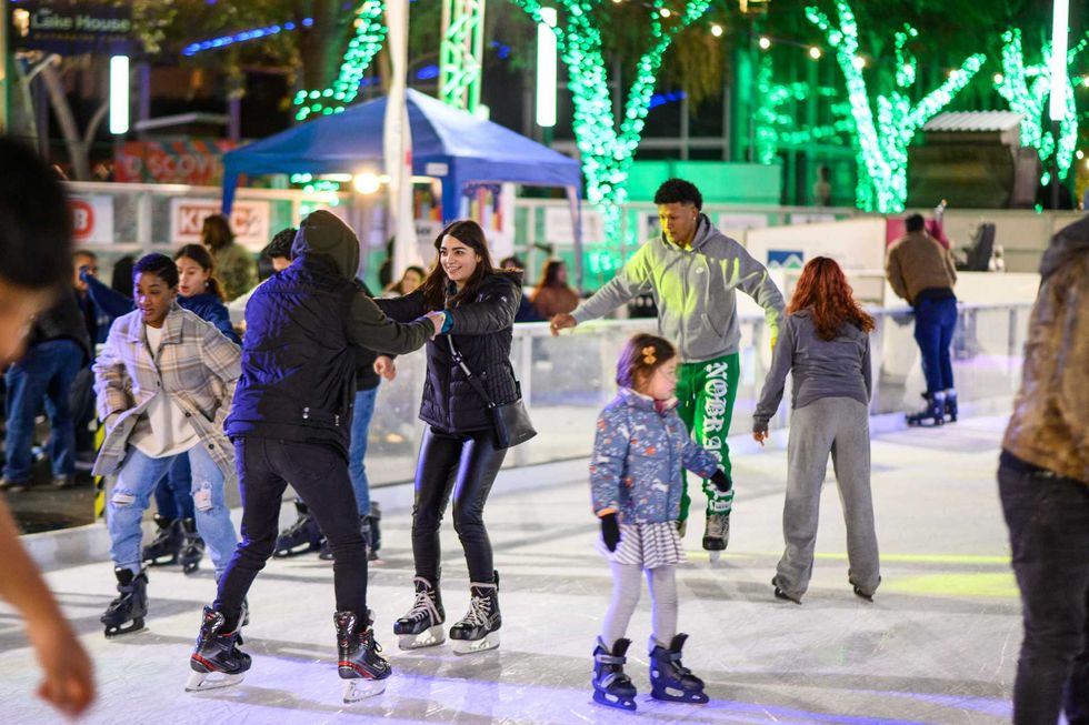 Ice skaters on an outdoor rink, two holding hands