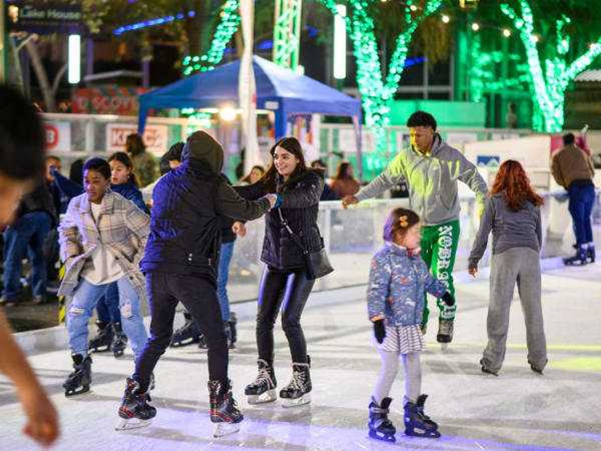 Ice skaters on an outdoor rink, two holding hands
