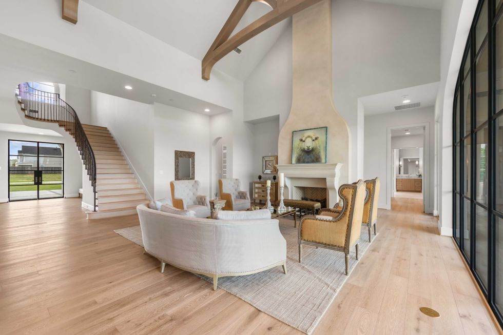 Interior of 4233Two Gun Way, showing the living room with a sweeping staircase and floor-to-ceiling windows