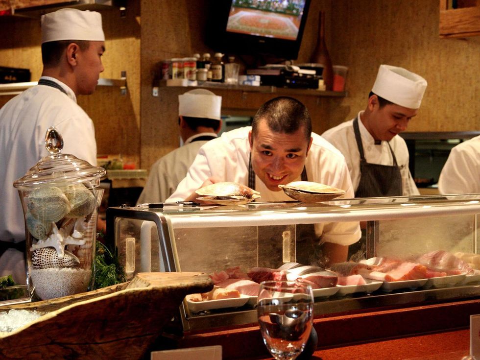 Kata Robata Sushi + Grill Chef Manabu Horiuchi cheking out live scallops before preparing