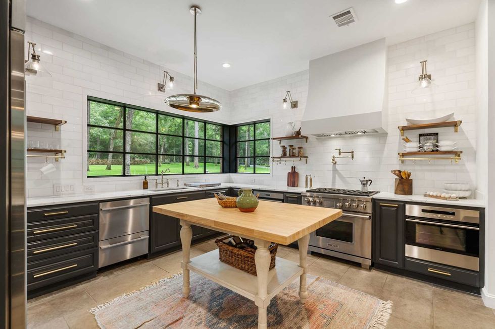 Kitchen of 23227 Brownwood Lane with a stove, warming oven, hardwood floors, and windows overlooking a tree-lined yard
