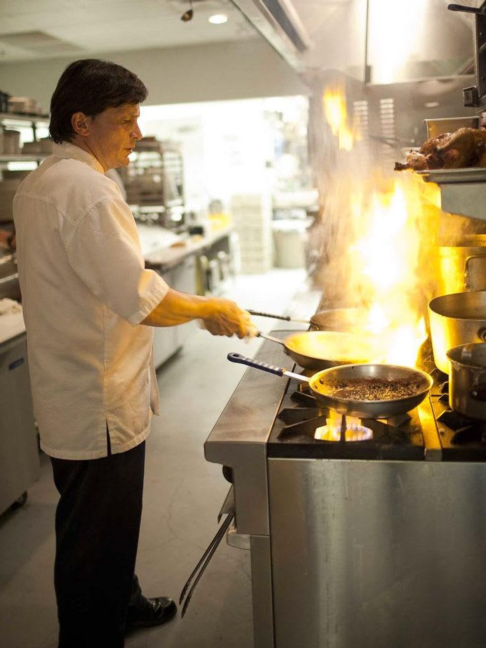 L\u2019Olivier Restaurant chef Olivier Ciesielski in kitchen cooking with flaming stove