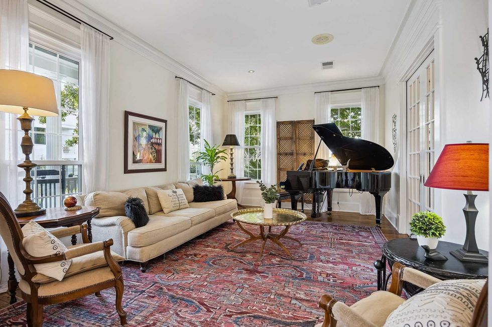 Living room of 216 E. 26th St. in the Heights, showing a piano, and several windows