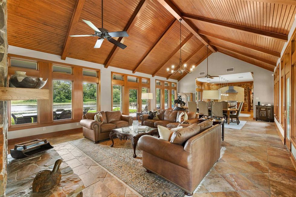 Living room of S Lazy S Ranch at 8502 Stansberry Road in Wallis showing vaulted wood ceiling and views of the lake outside the windows.