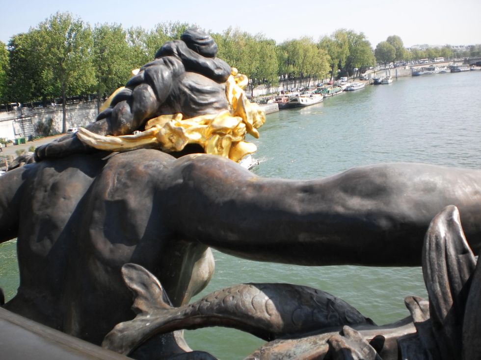 Looking down the Seine over the shoulder of nymph sculpture decorating Pont Alexandre III in Paris