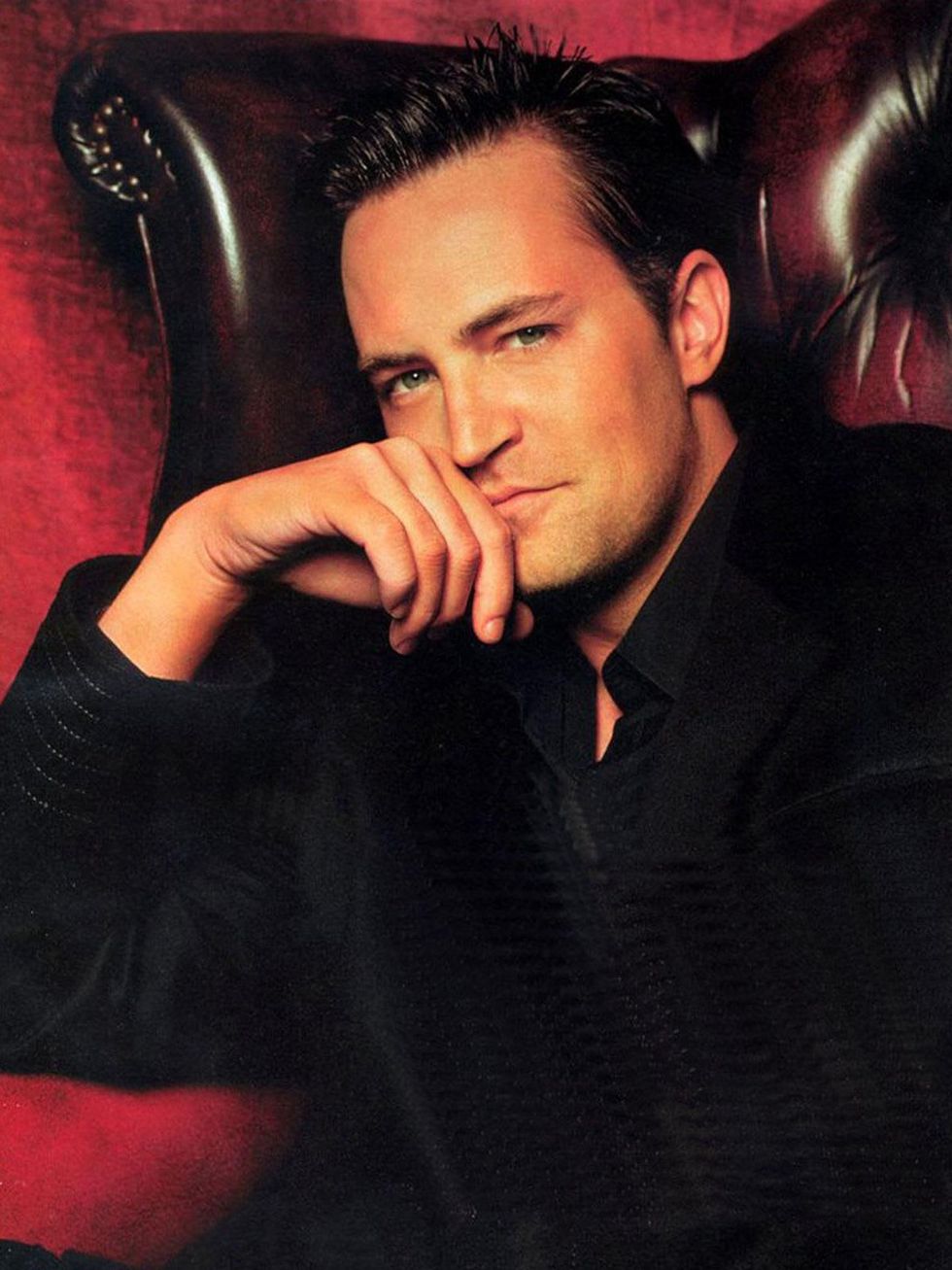 Matthew Perry in leather chair with red background