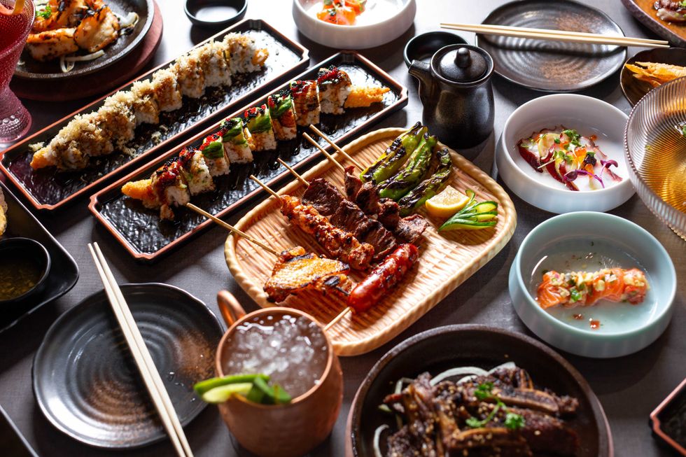 Multiple plates of sushi, sashimi, and grilled meats at Seven Sushi & Robata