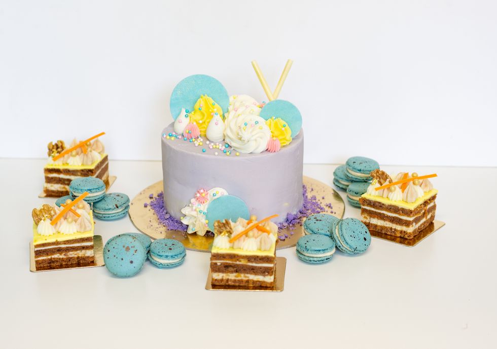 Photo of carrot cakes, blue speckled macarons and a purple iced cake.
