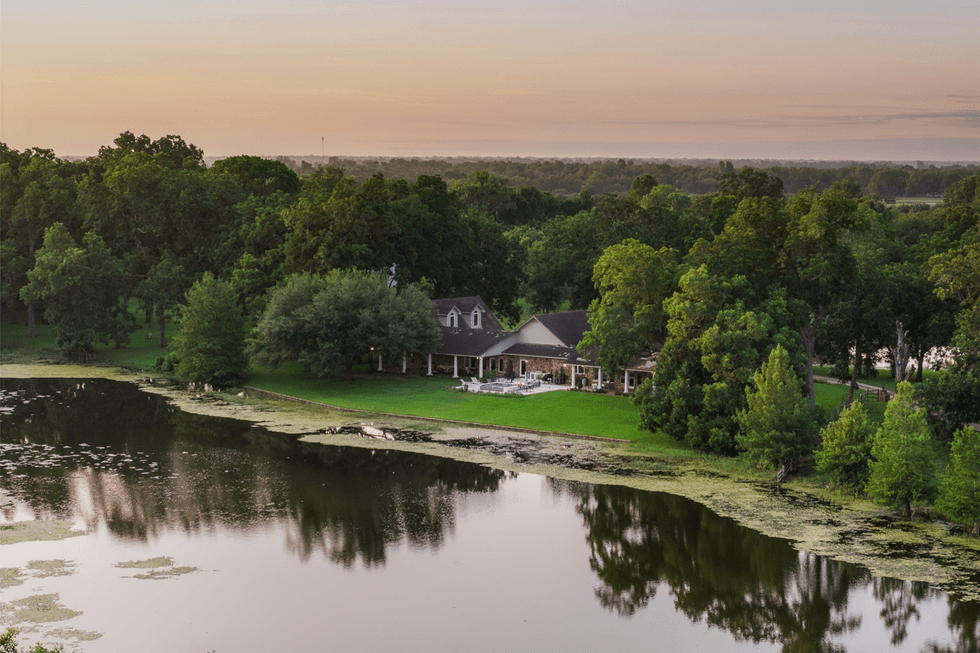 Photo of the S Lazy S ranch house, set back on a green lawn acbove a pond