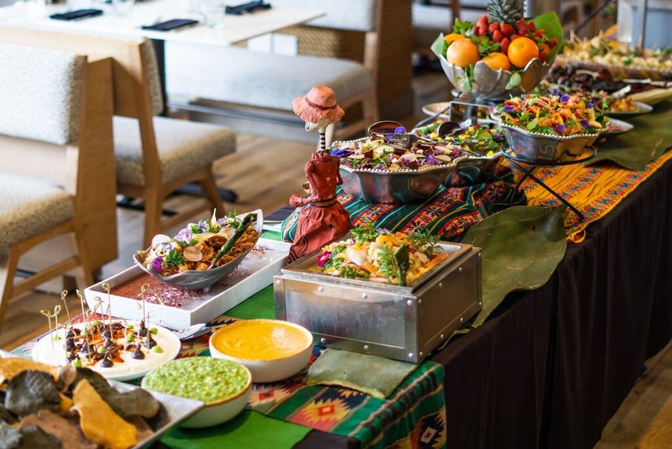 Picture of a brunch buffet on a table, with salads, salsas and plaintains.