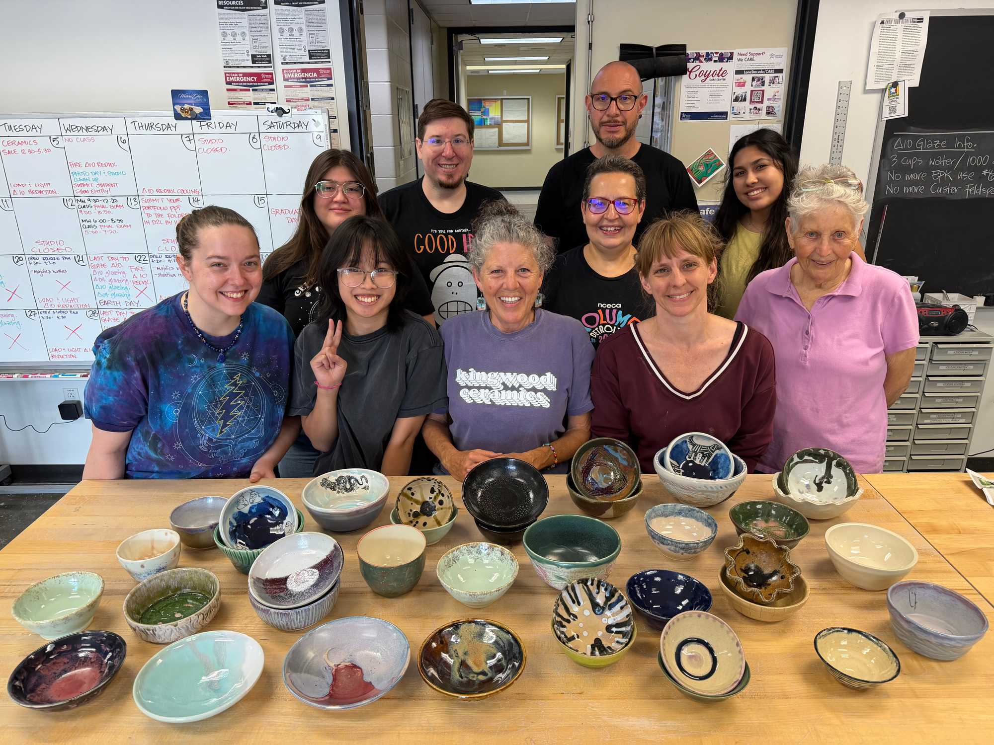 Picture of several artists at a table with a bunch of handmade ceramic bowls.