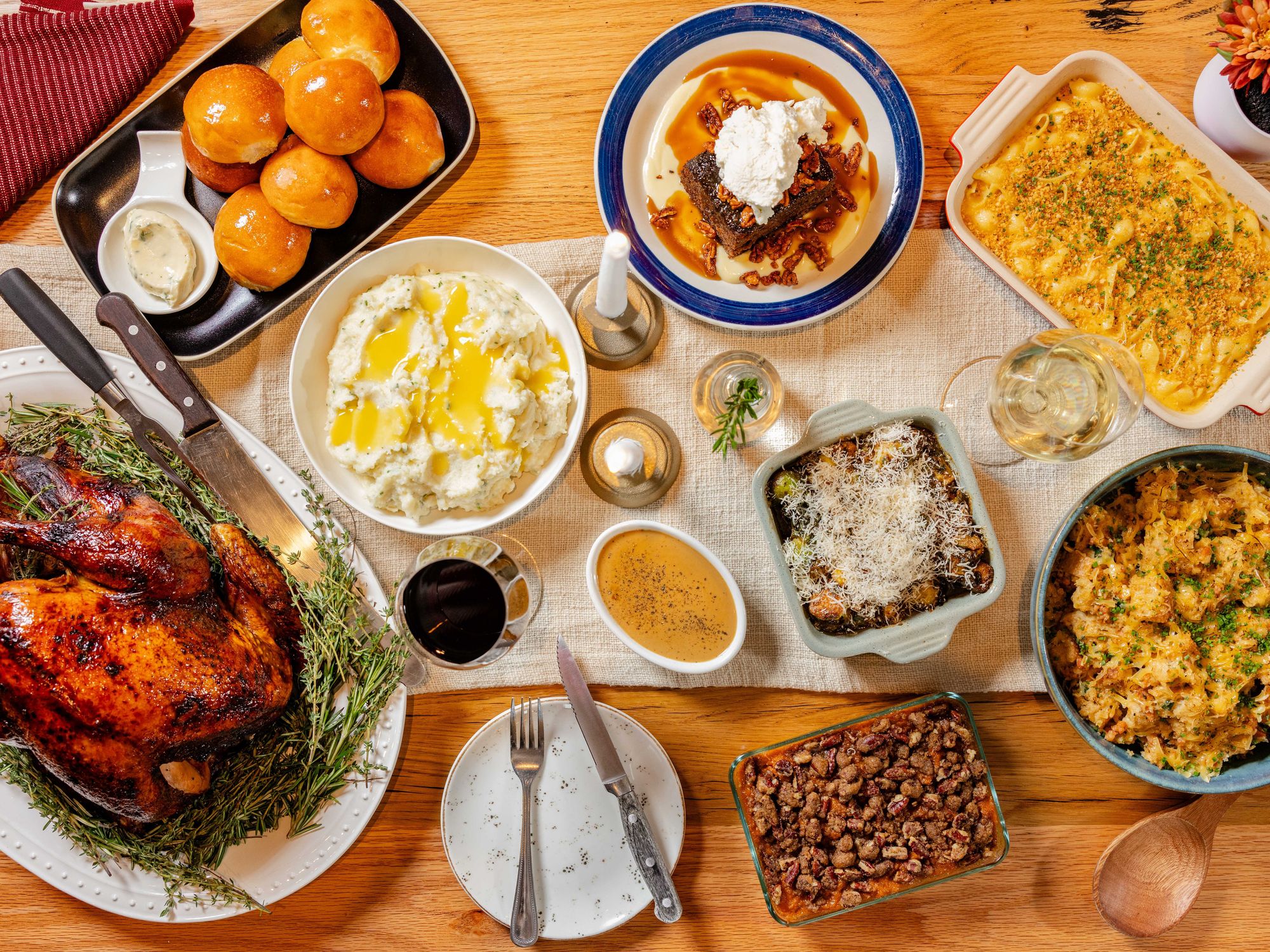 Picture of turkey and several sides, including mashed potatoes, green bean casserole, and rolls.